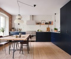 Una cucina blu incorniciata da mattoni a vista, piastrelle bianche e parquet naturale