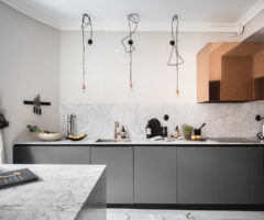 Una cucina grigia e marmo illuminata da alcuni dettagli color rame